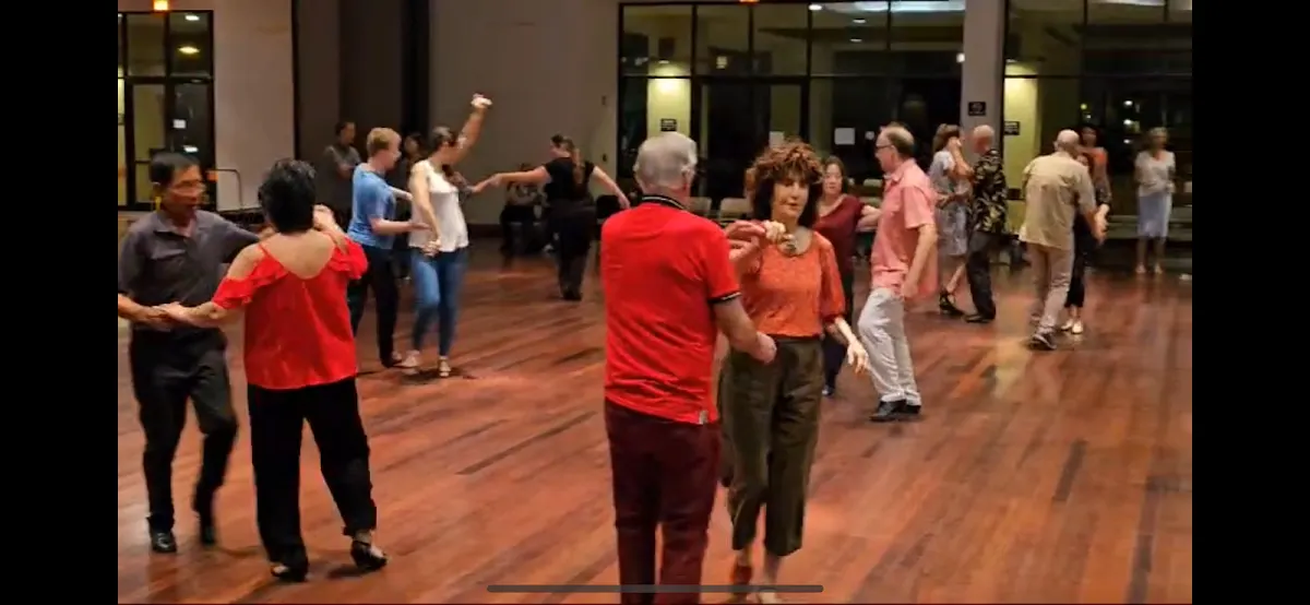 A lead and follow dancing a West Coast Swing pattern on the ballroom floor